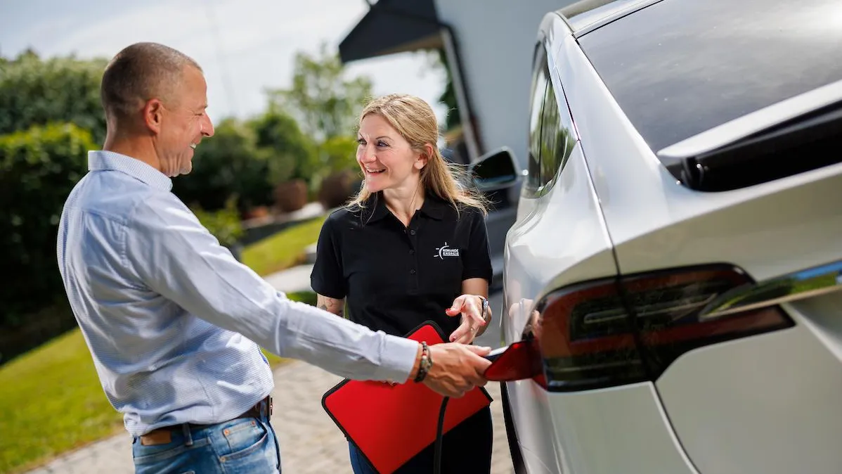 Homme chargeant sa voiture électrique sous les conseils d'une collaboratrice Romande Energie