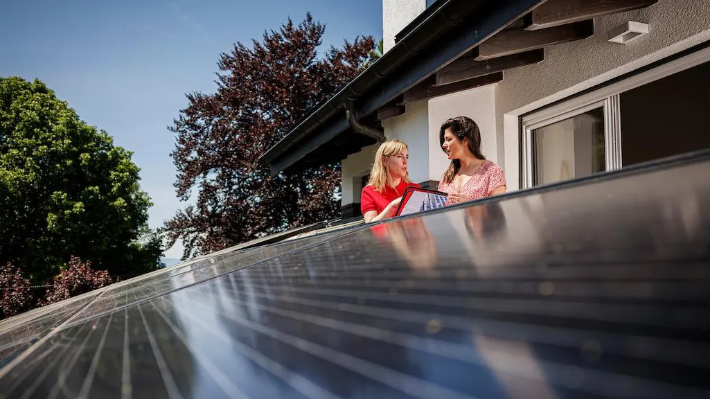 Commerciale Romande Energie avec cliente face à des panneaux solaires